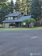 Charming two-story, architectural roof, and manicured landscaping. The front porch offers a welcoming entry with space for seating, framed by mature trees for privacy.