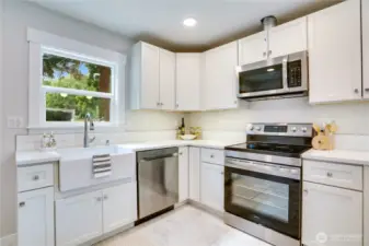 A perfect blend of style and function—this beautifully remodeled kitchen showcases a sleek new farm sink and a full suite of modern appliances, including a dishwasher, microwave, and range/oven. The elegant tile backsplash adds a polished finishing touch to this thoughtfully designed space.