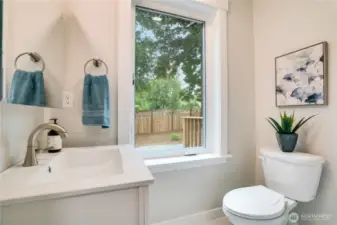 The updated en-suite half bath includes a new vanity and sink with new fixtures, fresh flooring, and a bright window for added natural light.