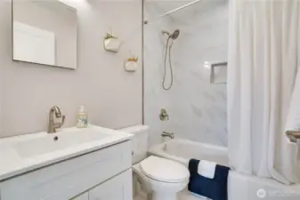 Fresh from top to bottom—tile floors, sleek vanity, updated fixtures, tile surround with bath accessory niche, and modern lighting create a spa-worthy main floor bathroom.