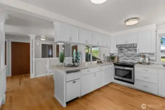 A modern kitchen with quartz countertops, stainless steel appliances, and crisp white cabinetry.