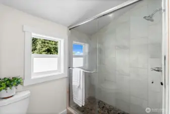 The primary bathroom is spacious and luxurious, featuring quartz countertops and tile floors.