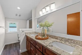 A well-appointed guest bath with hard surfaces and a tile-lined shower.