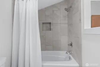 A well-appointed guest bath with hard surfaces and a tile-lined shower.
