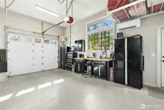 A large garage with high ceilings and garage doors, lots of natural light and epoxy floors.