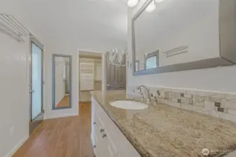 Primary bathroom featuring dual sinks, offering personal space. Walk in closet and door leading to back deck.