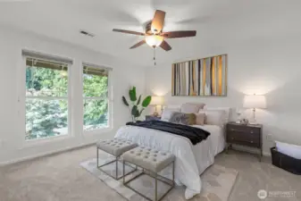 The primary bedroom with Southerly facing windows and ceiling fan lights