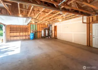 Three car garage with pedestrian door and built in shelving. Notice two water heaters and a well maintained gas furnace.