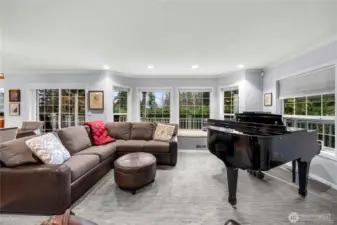 A large wall of window with a window seat look out to the sunset and the wrap around deck.