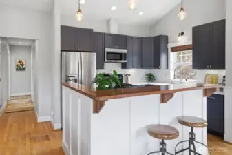 Great kitchen island with view of hall headed to primary, two beds and full bath.