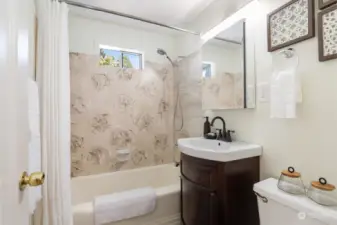 Full bathroom on main level of home includes new flooring, tile, lighting and medicine cabinet.