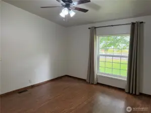 Primary bedroom with ceiling fan and large windows.