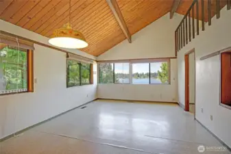 Large dining and living room with loft above and primary bedroom entrance to the right.