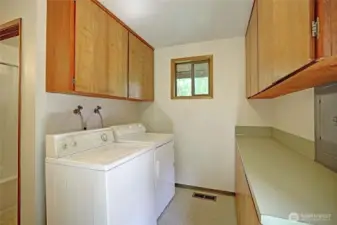 Utility room with washer and dryer included in addition to plenty of cabinet and storage space.