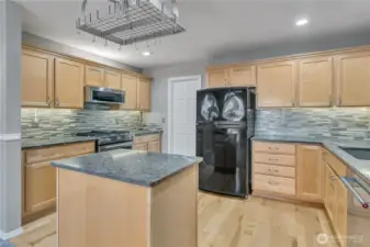 Chef’s kitchen with abundant cabinetry and quartzite counters. Full-height backsplash adds a stylish modern touch.