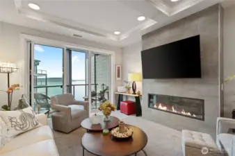 Contemporary living room dedicated space, cozy electric fireplace, oversized sliders – perfect Puget Sound views open to a private balcony for seamless indoor-outdoor living and entertaining.