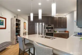 Open-concept kitchen with a spacious island, ideal for casual dining and entertaining. Custom cabinets, floor-to-ceiling pantry with pull-out shelving for easy access; One of two pantries (the other is a walk-in by the laundry room).