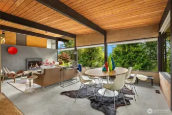 The wall of living room windows wraps around the adjacent very spacious dining area, which opens to a covered west-facing patio and deck.