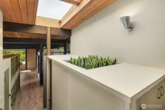 We've got faux plants here, but that's a real, functional planter with external drainage and everything!  A large skylight graces the upper bedrooms, landing, and main entry with natural light.  The door to the 2-car attached garage is just to our right.