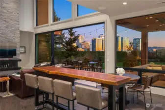 Two story living room has a wall of glass that opens to extend the indoors out.