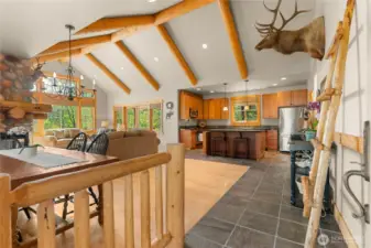 Vaulted great room with exposed beams, stone fireplace, and open layout.