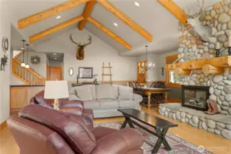 Inviting great room with vaulted wood-beam ceilings, river rock fireplace, and a blend of wood and slate flooring.
