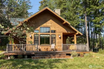 Classic Northwest lodge-style home with stone chimney and timber details, blending naturally into the forested setting.