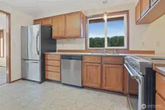 Kitchen features oak cabinets, stainless appliances including a newer kitchen aide downdraft range, an eating bar and opens to family room.