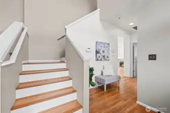 A Grand Welcome. The transition from the foyer to the upper level is defined by clean lines and a sense of scale. The wide staircase with crisp white trim and warm wood treads leads to the private quarters, while a cozy nook nearby offers a perfect spot for an entryway bench.
