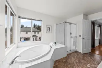 A Peaceful Escape. The oversized soaking tub is positioned perfectly under large windows, allowing you to enjoy views of the outdoors in total privacy. The crisp white tile and neutral tones create a clean, serene environment throughout the space.