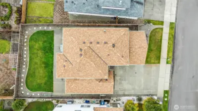 Aerial Perspective. This top-down view showcases the generous lot size and the excellent condition of the roof and exterior. Notice the seamless integration of the patio, lawn, and professional landscaping.