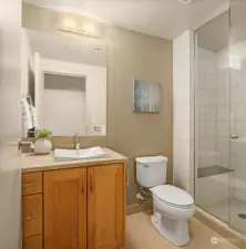 Bright three quarter guest bath just off the entry hallway includes a tile shower with a bench.