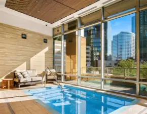 The attractive indoor community pool area with floor-to-ceiling windows overlooking the cityscape.