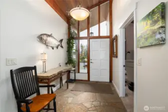 Large stone entryway with light-filled windows.  Family room/office space is to the right.