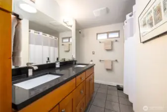 Full bathroom with maple cabinets and double sinks is located in the hallway, near the bedrooms and kitchen.