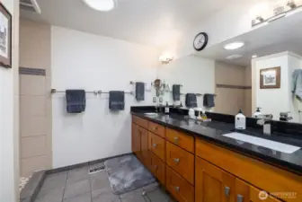 Remodeled primary bath with a large shower, tile floors and double sinks.