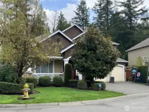 Mature trees and flowering shrubs grace the front yard