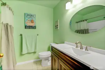 Main hallway bathroom, conveniently near bedrooms and ideal for guests, features a combo tub/shower, updated vanity, sink, toilet, and tile flooring.