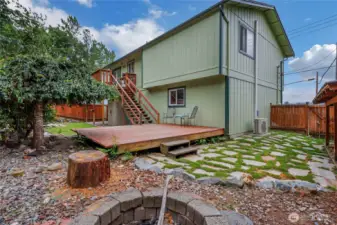 The lower deck opens to a side yard with paver walkway and a cozy fire-pit area—ideal for entertaining and relaxing outdoors.