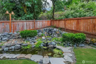 Tranquil backyard oasis featuring a serene water feature with pond and gentle waterfall.