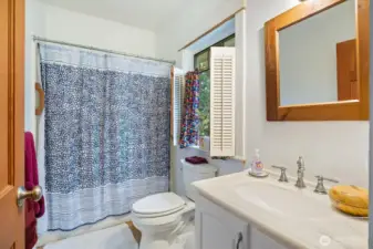 Second bedroom bathroom with bathtub/shower and charming shutter details