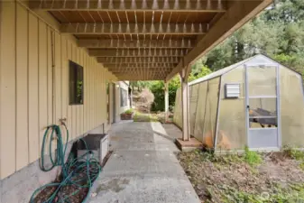 Lower level exterior with greenhouse and patio
