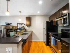 The kitchen is very efficient and have gray quartz countertops, dark cabinets and stainless steel appliances.