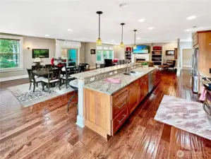 View of the gathering room from the corner of the kitchen.  Notice the rich wood floors, gas fireplace with built-in surround and slider to covered rear patio.