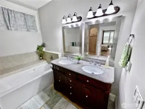 Elegant primary bath with soaking tub, full tile walk-in shower, double sink vanity, heated tile floor and large walk-in closet.