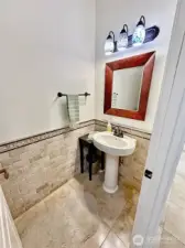 Elegant powder Room with pedestal sink, Travertine tile floor and wainscotting style, tile walls.