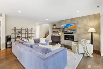 Large great room with high ceilings and grand chef's kitchen. Gas Fireplace, custom mounted TV, floor to ceiling tile surround.