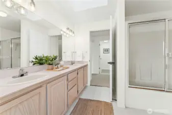 Guest bathroom with double sinks and a shower/tub combo with glass doors.