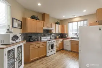Sunny kitchen has lots of storage.  Newer retro inspired appliances.  Notice the extended tile back splash.  Newer luxury vinyl plank flooring is beautiful and easy care.