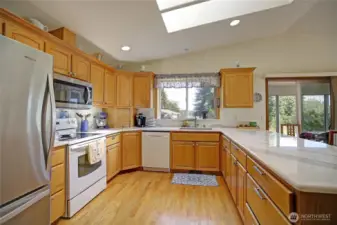 Chef's kitchen with stainless steel refrigerator and microwave, granite countertops, wood floors, ample cabinet space and more!